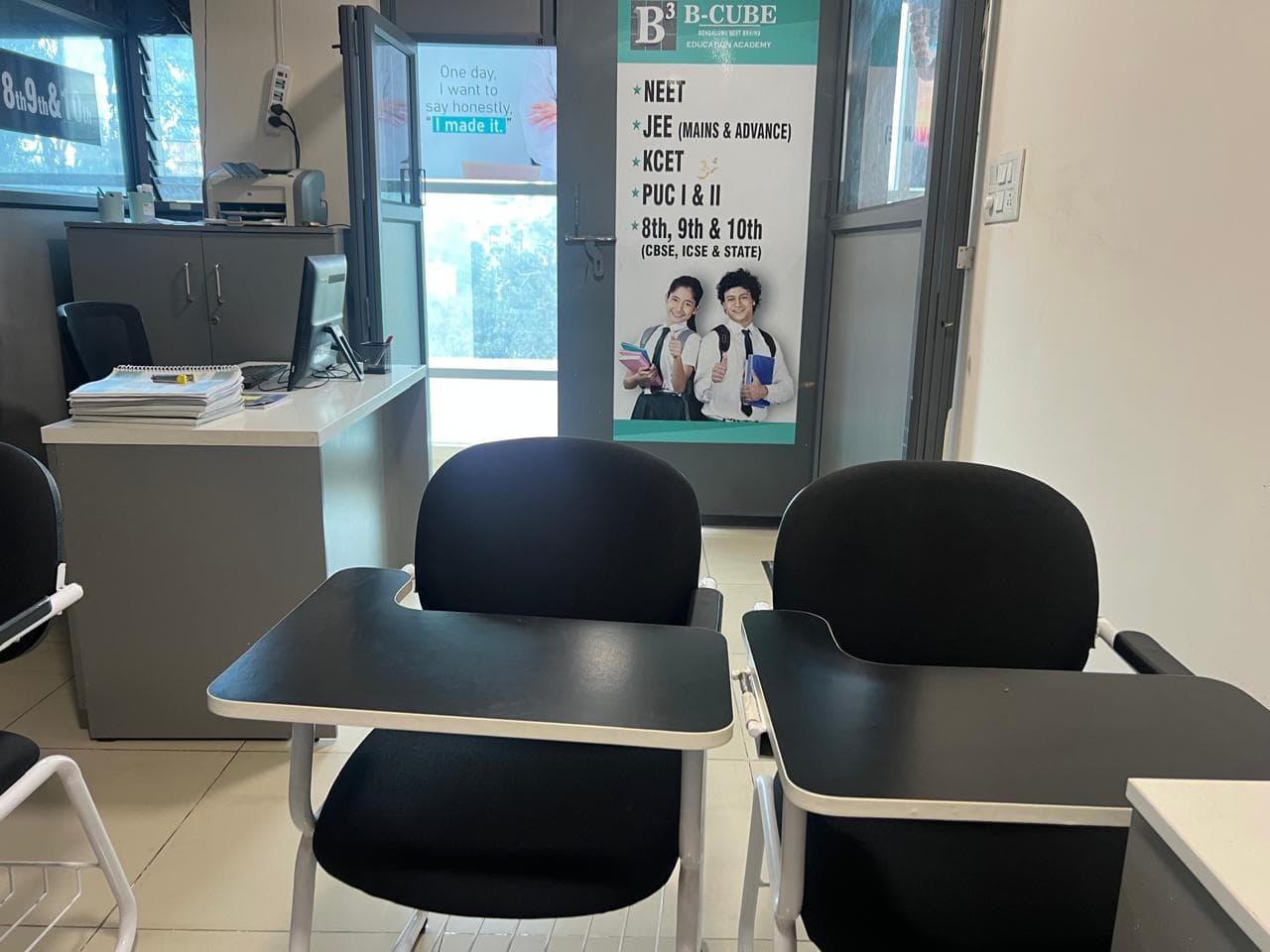 Student desks in front of a B-Cube banner listing NEET, JEE, K-CET, PUC and grades 8 to 10