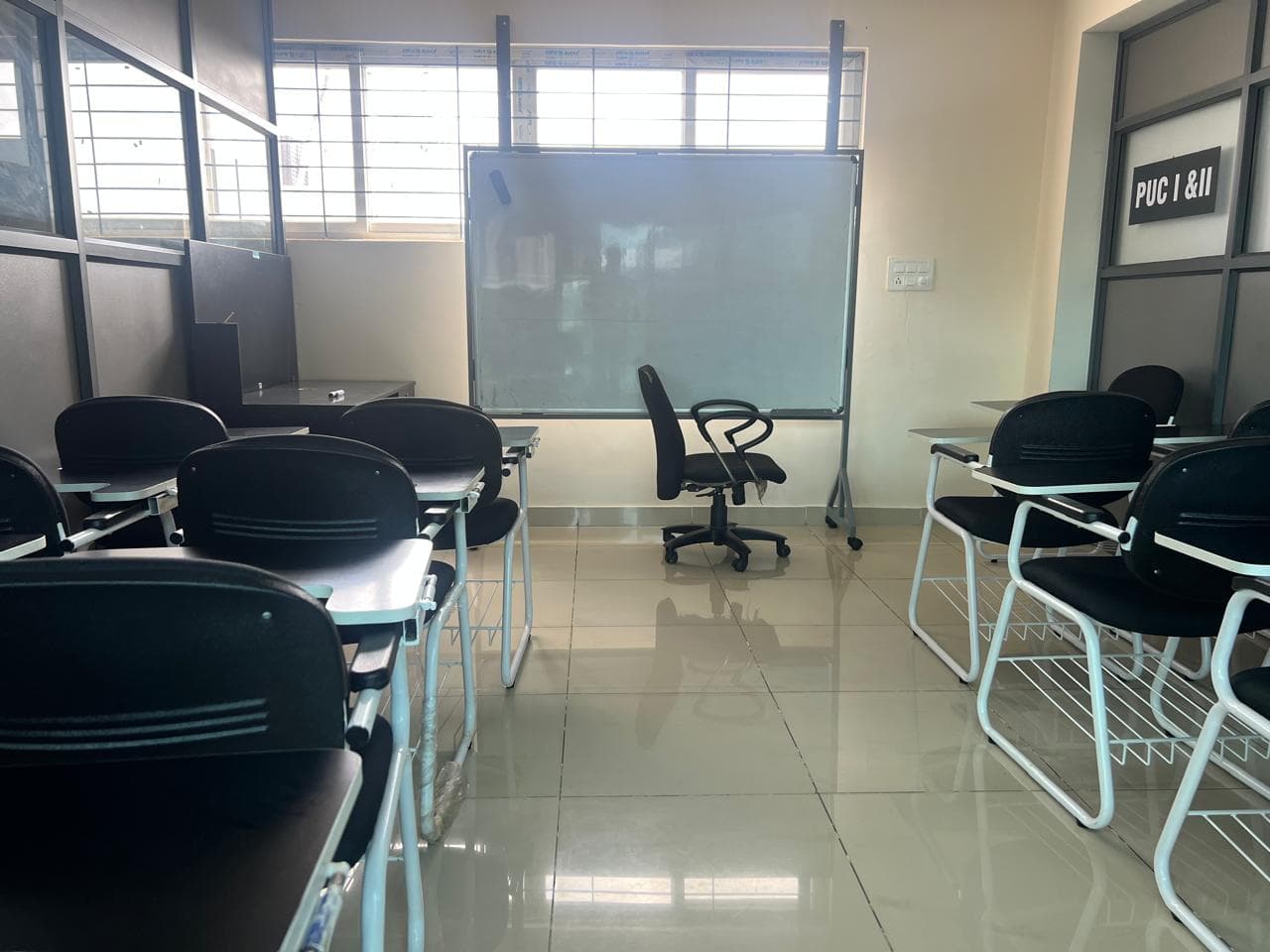 An empty B-Cube classroom with a whiteboard, a PUC I and II sign and rows of student desks