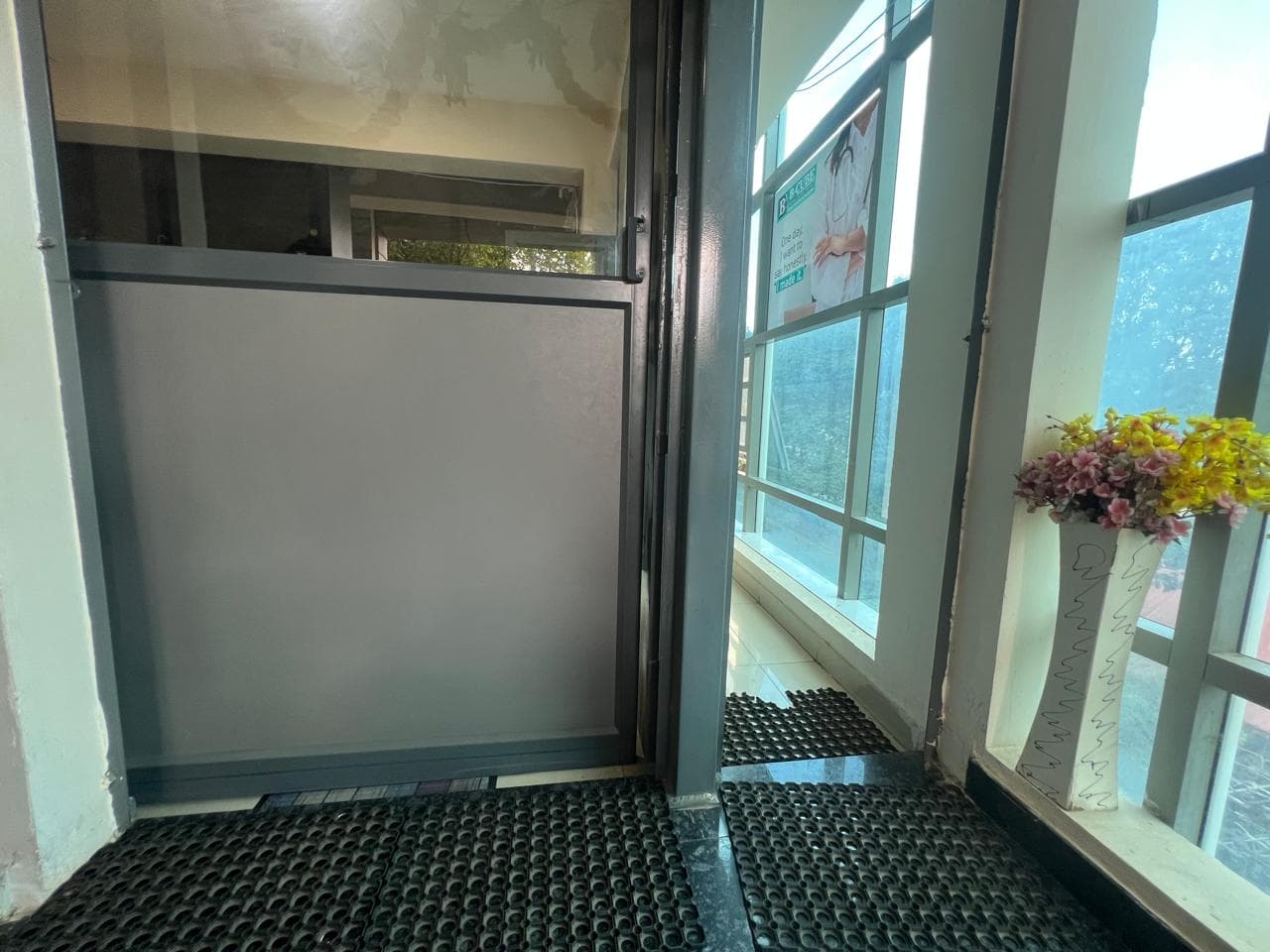 The entrance staircase of B-Cube with a frosted glass door and a vase of fresh flowers